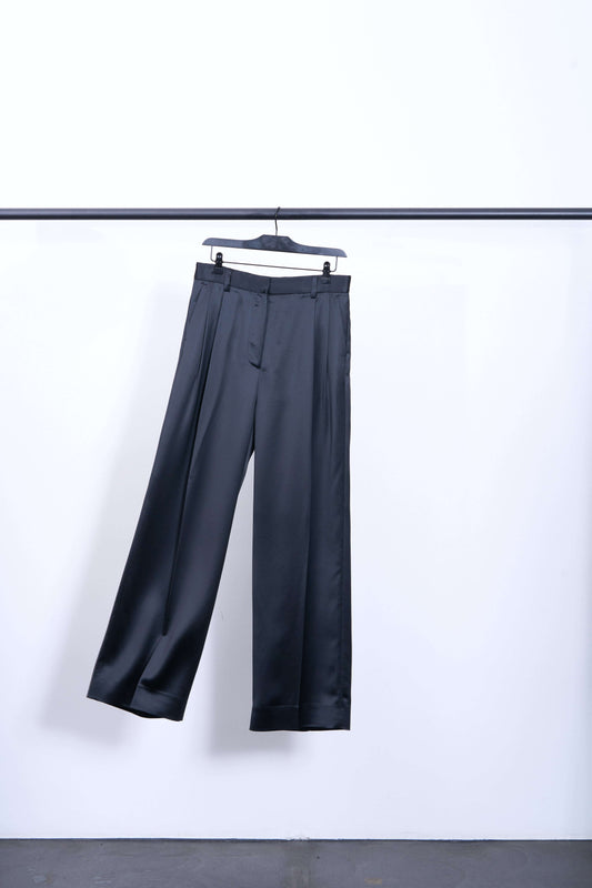 DARCEY SATIN TROUSERS hanging on a black hanger against a white background showcasing their glamorous shine and wide legs.