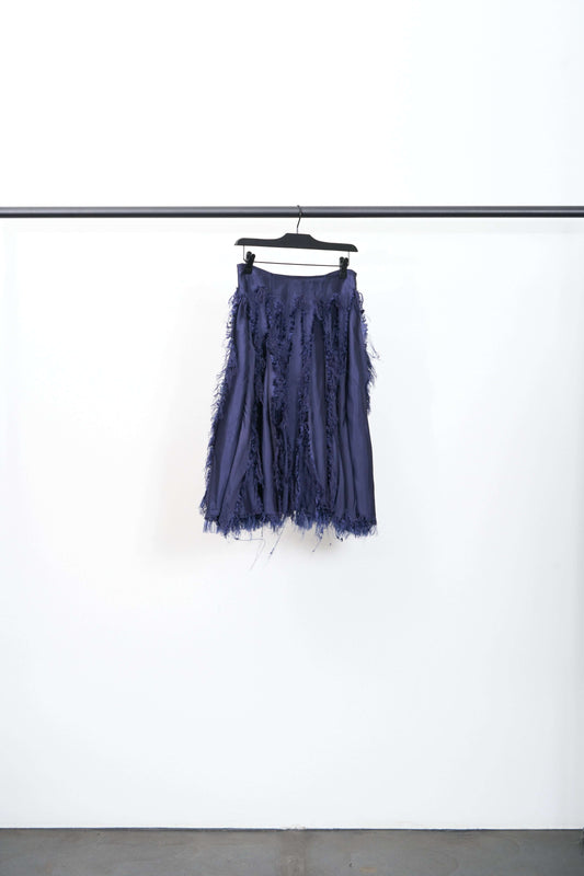 SCRATCH THE ITCH COLLEGE SKIRT in navy hanging on a rack, showcasing its unique design and comfortable fabric.