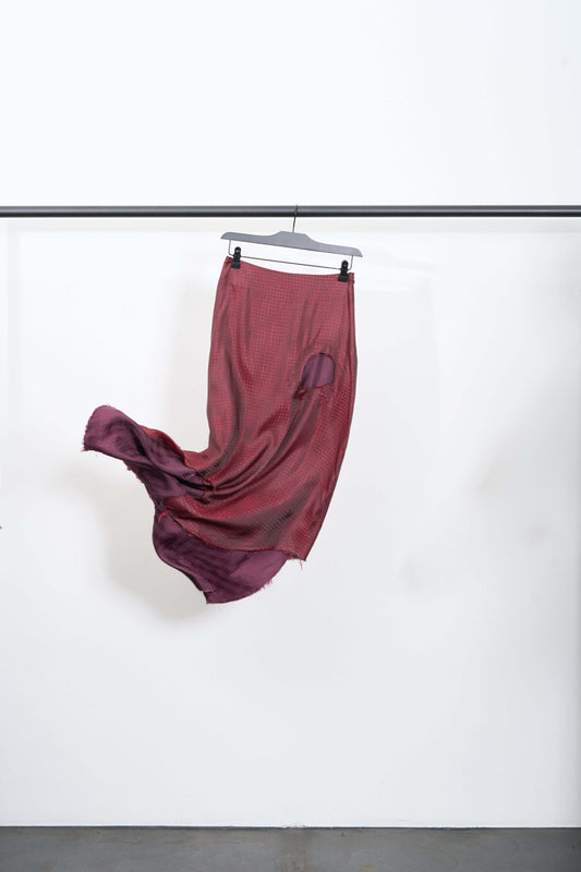 SIDE VIEW SKIRT hung on a hanger showcasing deep red and aubergine fringed cut-outs, mid-length design.