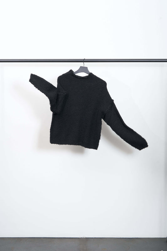 NEMURI SWEATER displayed on a hanger, showcasing its rustic black wool blend and relaxed silhouette.