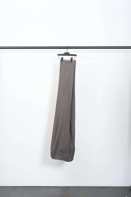 TAPER TROUSER hanging on a hanger against a minimalist background, showcasing the straight-leg design and wool fabric.