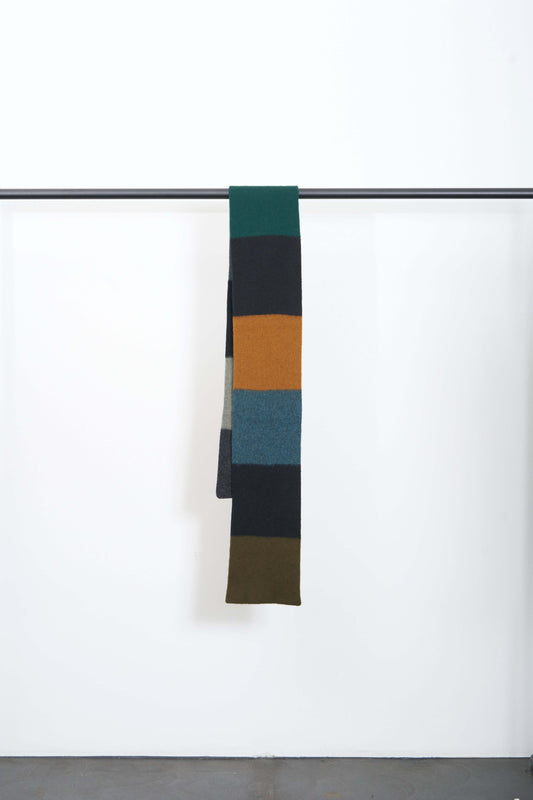 BRUSHED COLOURBLOCK SCARF hanging on a rack, showcasing soft lambswool and a vibrant color block pattern.