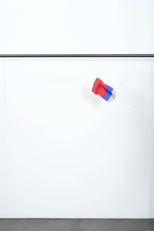 Colorful TOP-VIEW BEANIE in red, blue, and yellow stripes suspended against a simple white background.