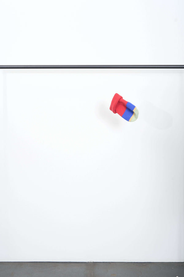 Colorful TOP-VIEW BEANIE in red, blue, and yellow stripes suspended against a simple white background.