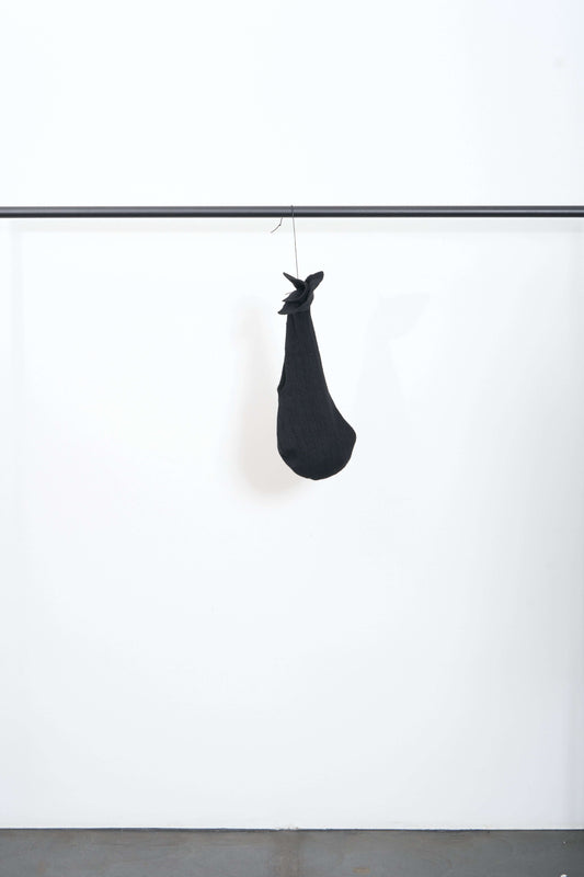 MIMI HEADPIECE hanging on a clothing rack against a minimalist background.
