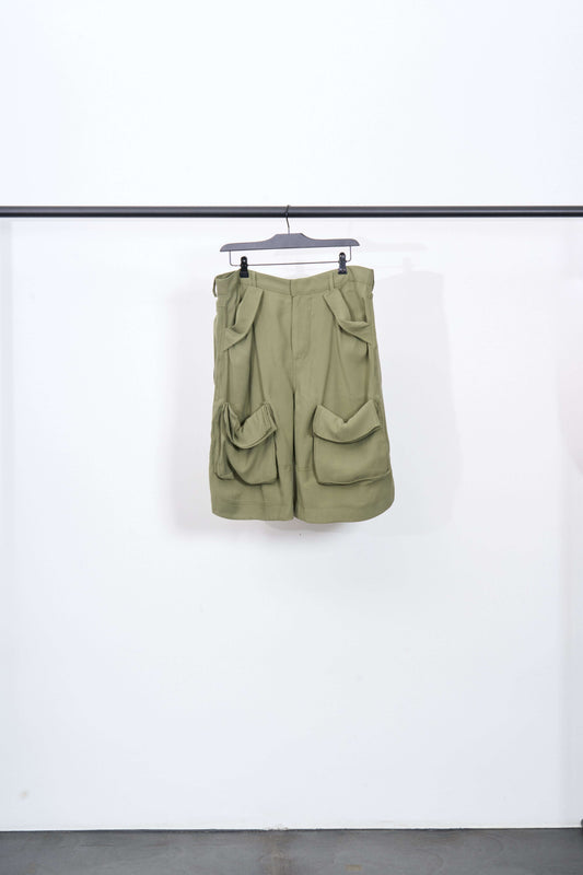 CARGO SAG SHORT in olive green, displaying its unique pocket design and brushed viscose fabric on a hanger.