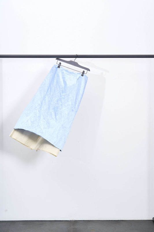 MUISHIKI SKIRT hanging on a black rack, showcasing its light-blue color and double-layered design.