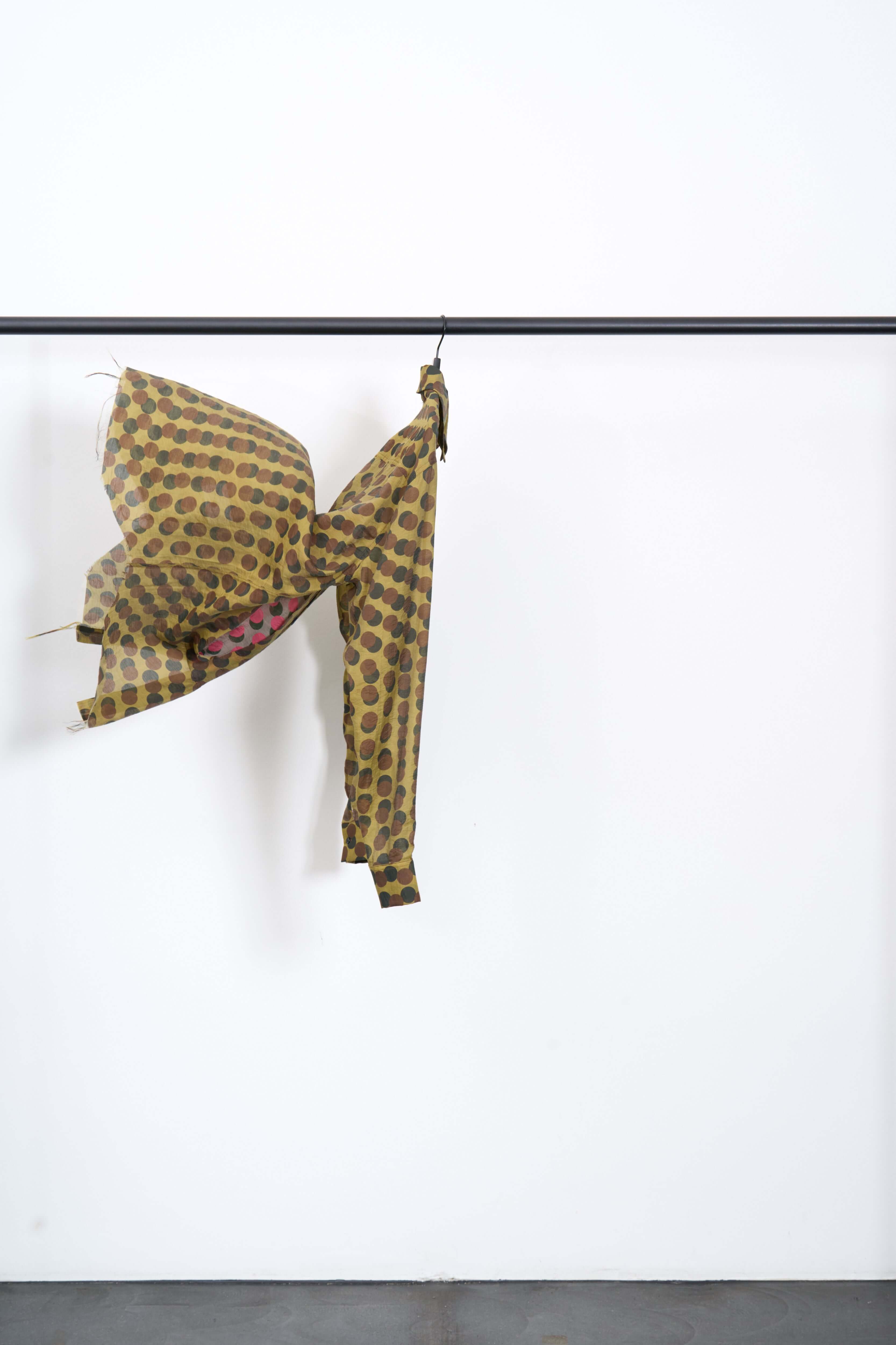 OPTICAL LUNG WINDOW SHIRT displayed on a hanger, showcasing the unique optical scales pattern in khaki brown.