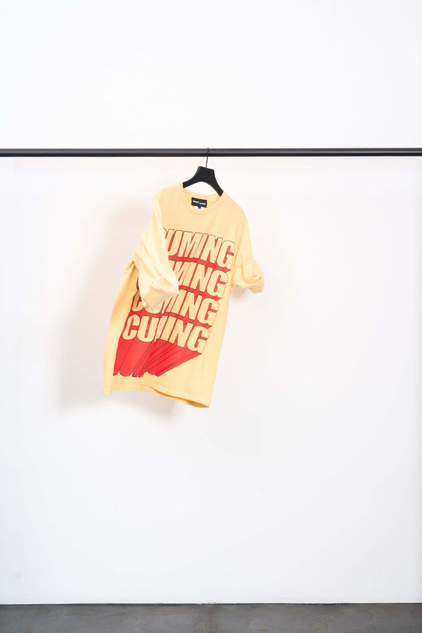 DAN MITCHELL CUMING OVERSIZED TEE in yellow cotton jersey with bold red CUMING print, hanging on display.