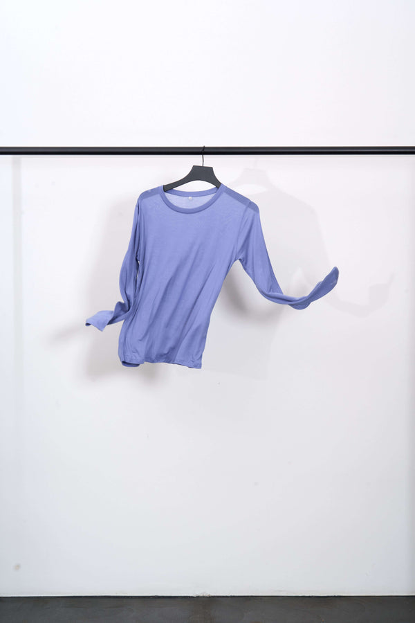 LONG SLEEVE TEE in light purple hanging on a hanger against a white background, slightly transparent and casual.