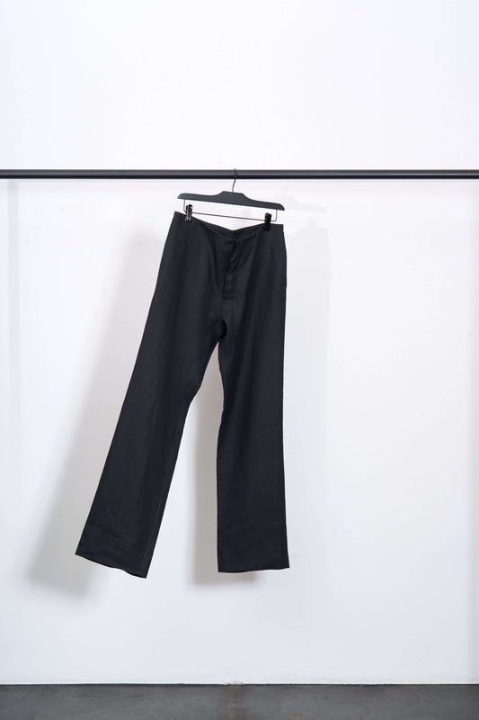 LINEN TAILORED TROUSERS hanging on a rack, showcasing a sleek design and lightweight fabric.