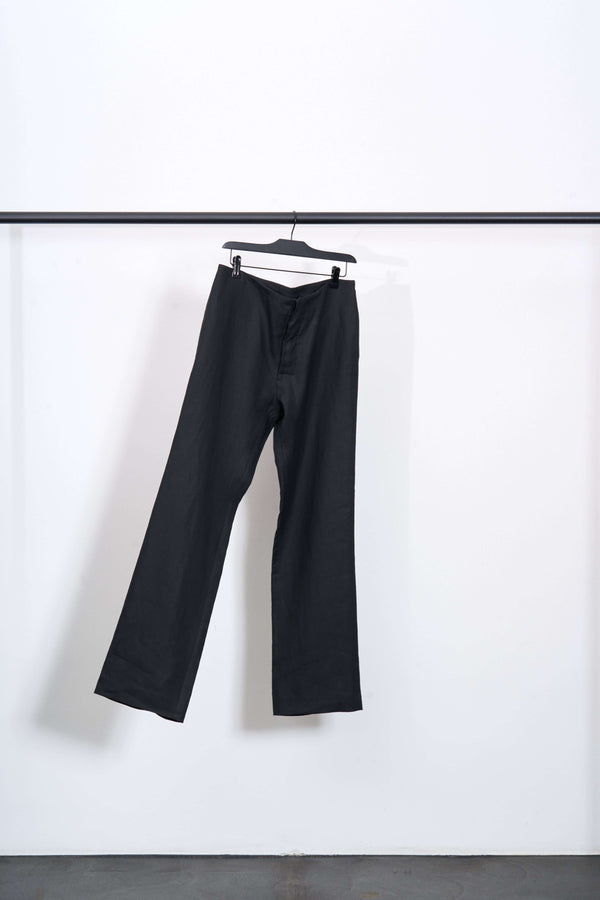 LINEN TAILORED TROUSERS hanging on a rack, showcasing a sleek design and lightweight fabric.