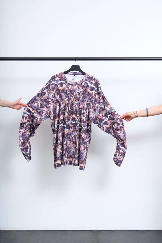 SHIRRING FALLEN ANGEL L/S TEE displayed on a hanger, featuring a colorful graphic design.