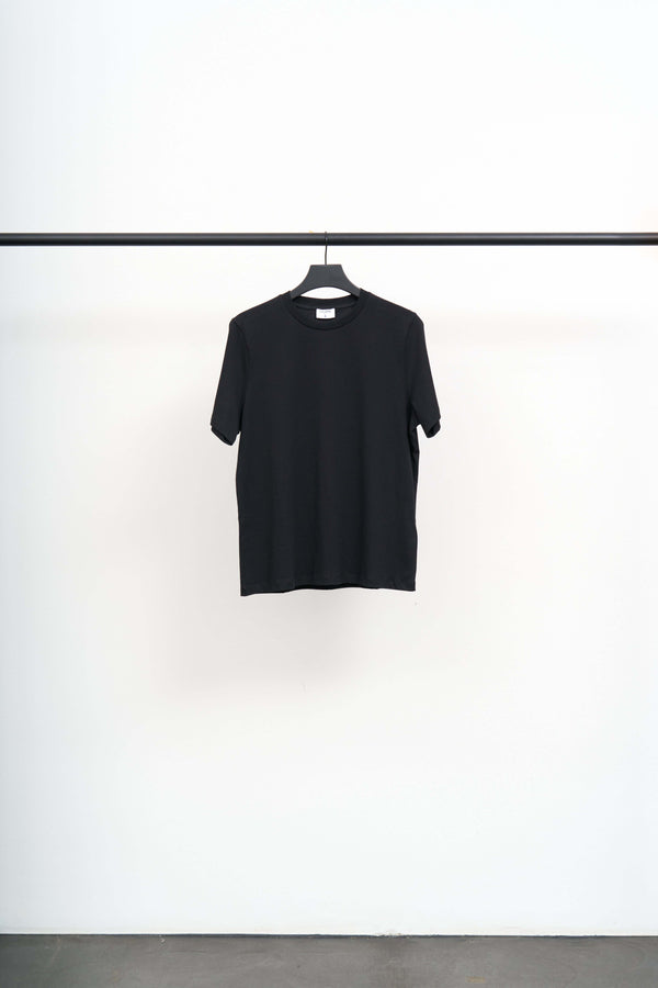FILIPPA TEE black t-shirt hanging on a rack, showcasing a regular silhouette and soft regenerative cotton jersey.