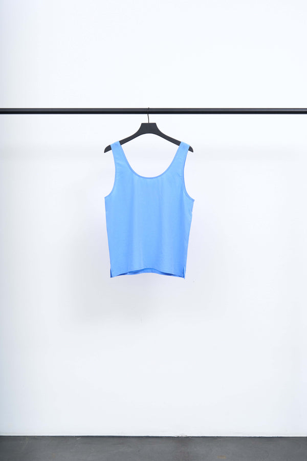 SIKA - LIGHT TENCEL SINGLET hanging on a black hanger against a white background, showcasing its vivid blue color.
