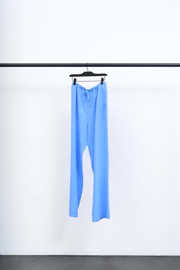 ANI - LIGHT TENCEL TROUSERS hanging on a rack, featuring a light blue color and relaxed fit for a stylish look.
