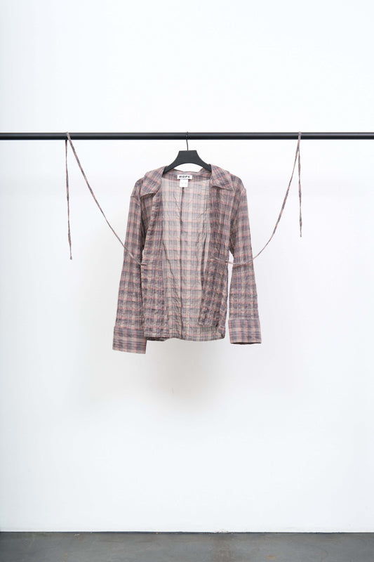 Front view of a LACE UP SHIRT on a hanger, showcasing its lightweight fabric and open silhouette tied at the front.