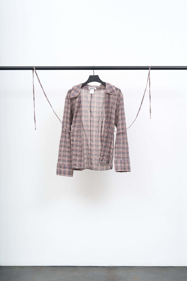 Front view of a LACE UP SHIRT on a hanger, showcasing its lightweight fabric and open silhouette tied at the front.