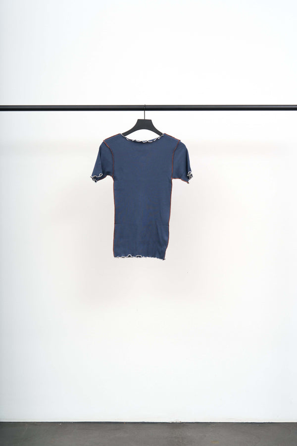 Back view of the VEIN T SHIRT hanging on a rack, showcasing its minimal design and contrast stitching details.