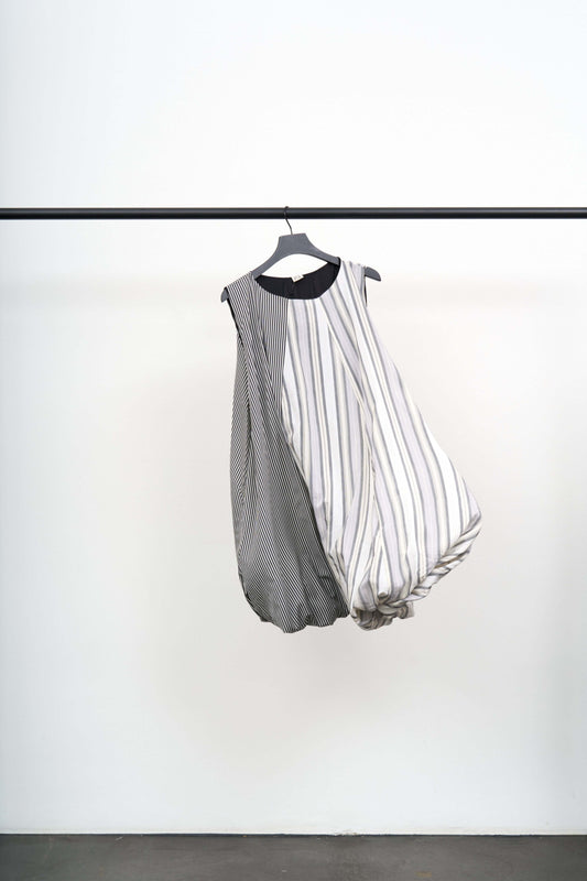 Bella Dress hanging on a rack, showcasing its sculptural design and unique silk cotton jersey texture.