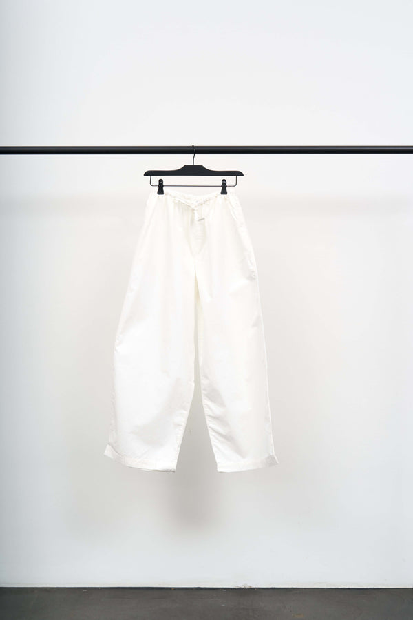 KOLLA PANTS on a hanger showcasing their wide leg and lightweight white fabric with a relaxed fit.